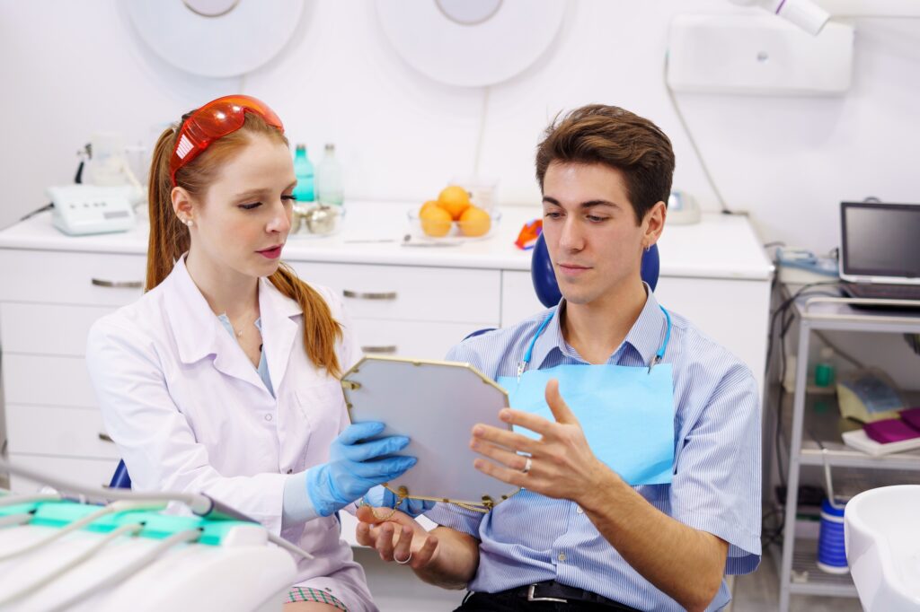 Female dentist giving mirror to male patient