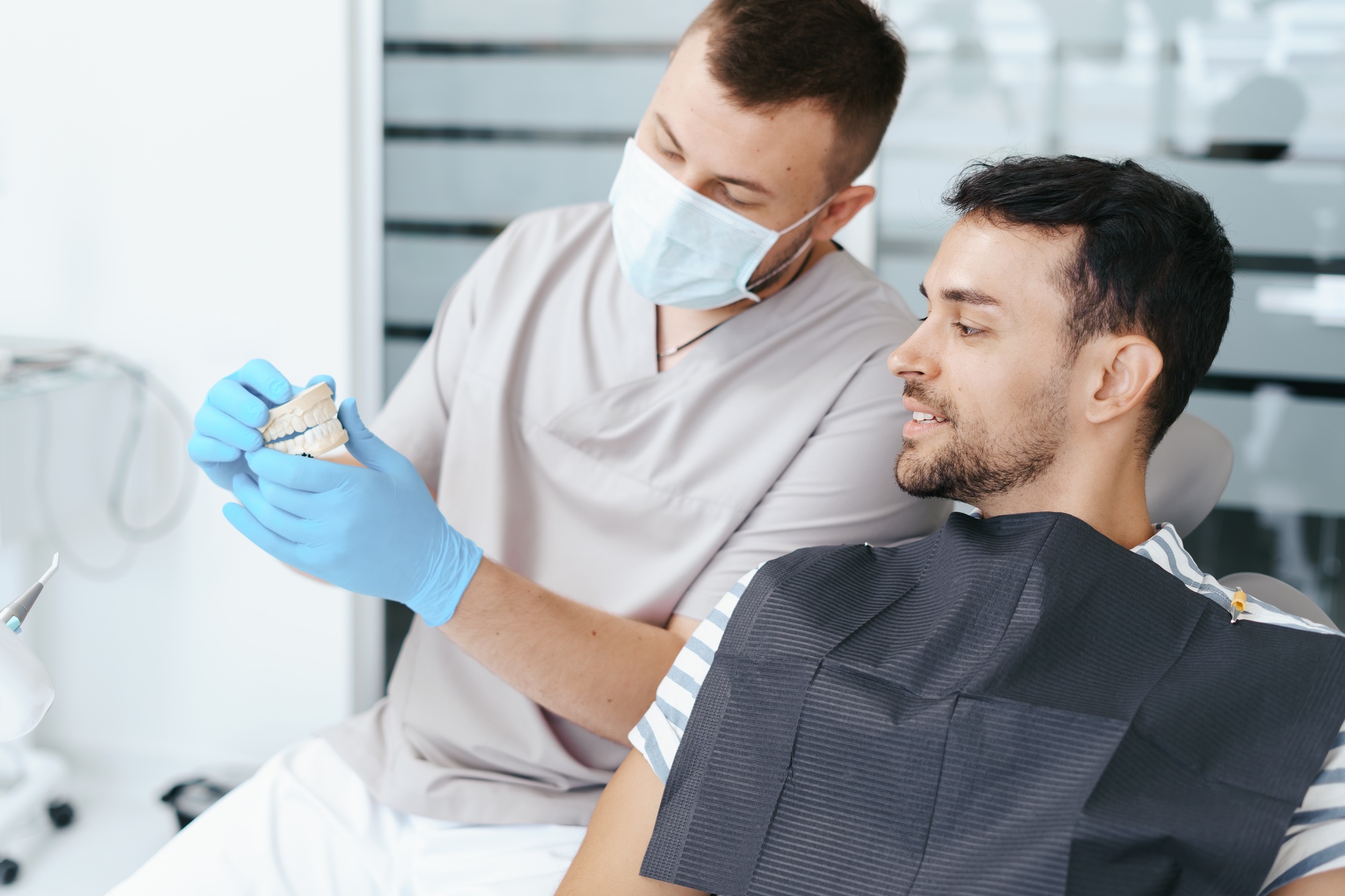 Male dentist showing patient the artificial dentures