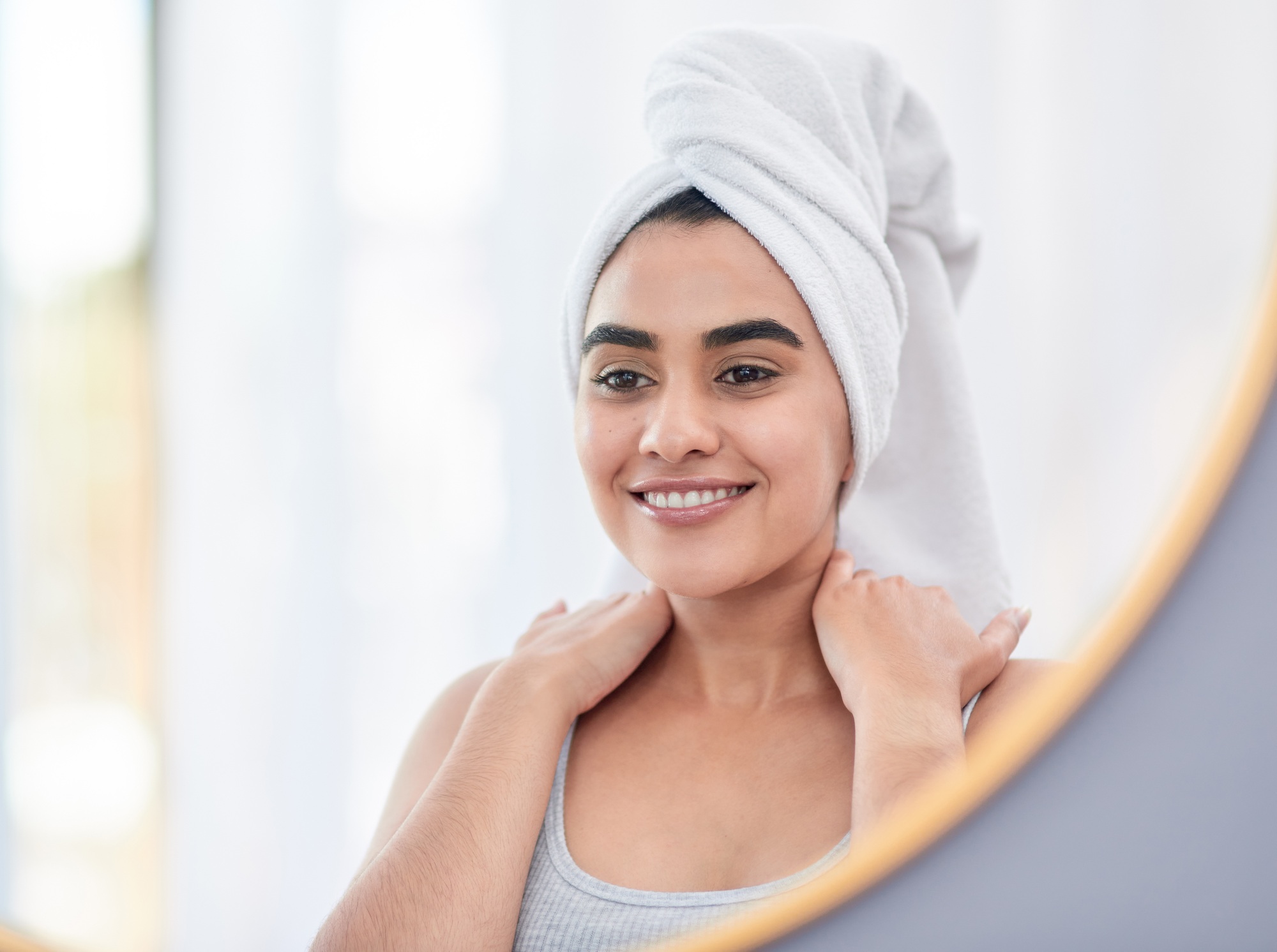 Shot of attractive young woman admiring herself in the mirror