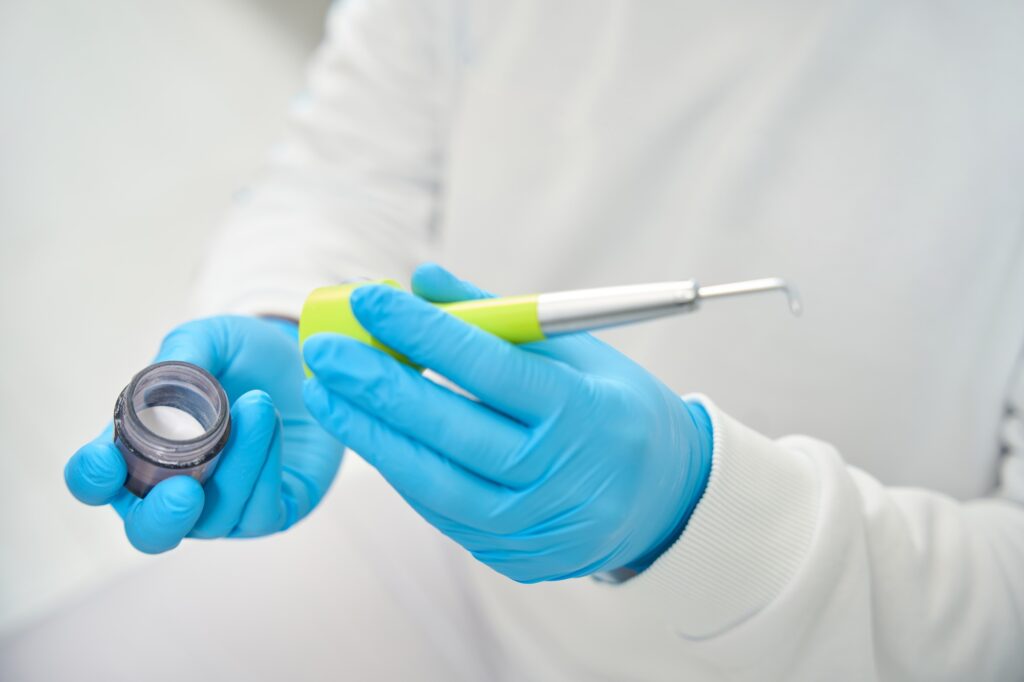 Qualified dental hygienist preparing air flow tool adding erythritol powder