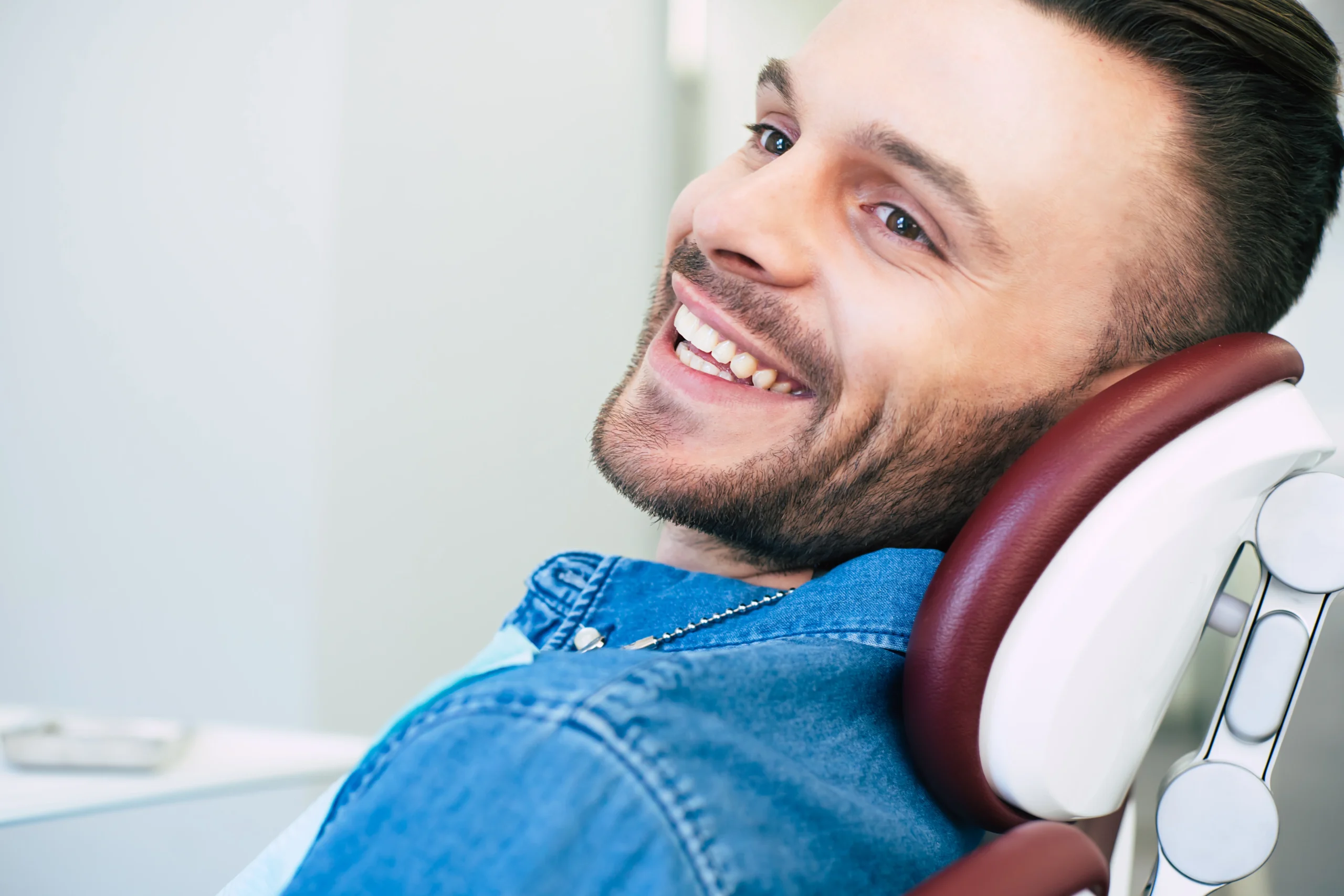 happy-man-with-hazel-eyes-dark-brown-hair-is-sitting-dental-chair-smiling-right-into-camera-because-he-is-satisfied-with-work-dentist-scaled.webp